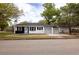 Inviting single-story home with white and black accents and an attached carport, nestled among mature trees and lush greenery at 5801 N 17Th St, Tampa, FL 33610