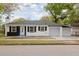 Charming single-story home featuring a black-and-white exterior, complemented by an attached carport and a well-manicured front lawn at 5801 N 17Th St, Tampa, FL 33610