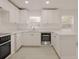 Bright kitchen with modern appliances, white cabinets, countertops, a breakfast bar and two windows for natural light at 5801 N 17Th St, Tampa, FL 33610