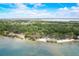 Aerial view showcasing a pristine beach, lush greenery, and tranquil lake waters at 611 Shore E Dr, Oldsmar, FL 34677