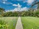 Inviting backyard featuring lush greenery, stone pathway, and decorative pergola with wooden gate for a tranquil setting at 6202 7Th S Ave, Gulfport, FL 33707