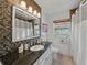 Modern bathroom features mosaic tiling, granite countertop, and ample lighting above the vanity mirror at 6202 7Th S Ave, Gulfport, FL 33707