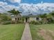 Charming single-story home featuring a lush landscaped front yard, brick path, and vibrant tropical foliage at 6202 7Th S Ave, Gulfport, FL 33707