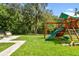 Lush backyard with green grass, landscaping, playground set, and stone-paved seating area at 6214 Windship Ct, Tampa, FL 33647