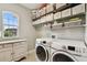 Bright laundry room features lots of storage, a window, and front load machines at 6214 Windship Ct, Tampa, FL 33647