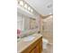Bright bathroom featuring a granite-topped vanity, a mirrored cabinet, and a glass-enclosed shower with beige-tiled walls at 704 Childers Loop, Brandon, FL 33511