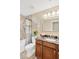 Bathroom featuring a bathtub with shower, a marble-topped vanity, framed mirror, and neutral-toned walls at 704 Childers Loop, Brandon, FL 33511