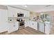 Modern kitchen featuring white cabinets, stainless steel appliances, and wood-look flooring at 704 Childers Loop, Brandon, FL 33511