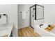 Sleek bathroom featuring modern fixtures, a glass-enclosed shower, a soaking tub, and wood-look flooring at 7611 Wood Violet Dr, Gibsonton, FL 33534