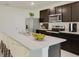 Modern kitchen with stainless steel appliances, dark wood cabinets, and a large island with seating at 7696 Wheat Stone Dr, Zephyrhills, FL 33540