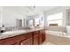 Elegant bathroom features granite counters, wooden cabinets, soaking tub, and glass enclosed shower at 8111 Brickleton Woods Ave, Gibsonton, FL 33534