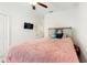 Carpeted bedroom with a white headboard, pink fuzzy blanket, a mounted tv, and ceiling fan at 8111 Brickleton Woods Ave, Gibsonton, FL 33534