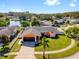 Aerial view of the home with a manicured lawn, a two-car garage, and circular driveway, situated in a scenic neighborhood at 8216 Damara Dr, New Port Richey, FL 34653
