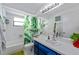 Well-lit bathroom with white vanity, blue cabinets, and tropical-themed shower curtain at 8216 Damara Dr, New Port Richey, FL 34653