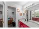 Bright bathroom featuring a large mirror, red vanity, white countertop, and decorative wall art at 8216 Damara Dr, New Port Richey, FL 34653