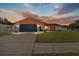 Charming single-story home at sunset with a well-maintained lawn, a two-car garage, and bright orange exterior at 8216 Damara Dr, New Port Richey, FL 34653