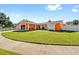 Single-story home with bright orange exterior paint, a two-car garage, and a well-maintained circular lawn at 8216 Damara Dr, New Port Richey, FL 34653