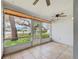 Relaxing screened-in porch with tile flooring, ceiling fan, and serene views of the lush landscaping at 8619 Gold Pine Dr, Port Richey, FL 34668