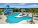 Exterior view of a luxurious community pool with a waterslide, lounge chairs, palm trees, and umbrellas at 9136 Warm Springs Cir, Parrish, FL 34219
