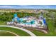 Aerial view of a luxurious community pool with a waterslide, lounge chairs, palm trees, and umbrellas at 9136 Warm Springs Cir, Parrish, FL 34219