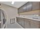 Laundry room features ample cabinet and counter space with gray cabinetry and stainless steel appliances at 9136 Warm Springs Cir, Parrish, FL 34219