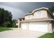 Charming home showcasing an attached two-car garage, neutral color palette, and mature trees at 10402 Ashley Oaks Drive, Riverview, FL 33578
