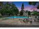 A community swimming pool surrounded by lush trees and picnic tables provides a refreshing escape from the summer heat at dusk at 125 Picardy Villa Cir # 100, Brandon, FL 33510