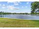 Scenic view of a calm pond surrounded by green lawn and trees, with residential houses in the background at 12501 Ulmerton Rd # 110, Largo, FL 33774