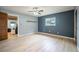 An empty bedroom with blue accent wall, wood floors, and a view to the living room at 13296 88Th N Ave, Seminole, FL 33776