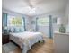 Cozy bedroom with light blue walls, wood floors, and natural light from two windows at 13296 88Th N Ave, Seminole, FL 33776