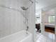 Bright bathroom with tiled walls, showerhead, and doorway view to bedroom at 147 114Th Ne Ave # 147, St Petersburg, FL 33716