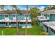 Rear exterior view of a blue townhome with patio, lawn, and some mature trees at 147 114Th Ne Ave # 147, St Petersburg, FL 33716
