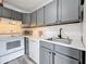 Updated kitchen showcasing gray cabinets, a stainless steel sink, and white appliances at 147 114Th Ne Ave # 147, St Petersburg, FL 33716