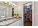 Clean bathroom with white cabinets, a spacious vanity, and an adjacent closet with shelving at 150 Bosphorous Ave, Tampa, FL 33606