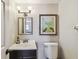 Bathroom with a sink, mirror, dark wood vanity and a toilet; a painting is on the wall at 150 Bosphorous Ave, Tampa, FL 33606