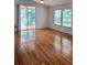 Sunlit living room with gleaming hardwood floors, multiple windows, and sliding glass door access to outdoor area at 1605 Send Way, Lutz, FL 33549