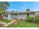 Charming house exterior with light gray siding, teal door, solar panels, and inviting walkway at 1841 Douglas Ave, Dunedin, FL 34698
