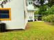 Side yard of a home, features green grass, landscaping, and a covered carport with a golf cart at 20989 Negril, Lutz, FL 33558