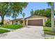 Charming one-story home featuring a brown two-car garage, well-maintained lawn, and inviting front porch area at 2329 Carrie Ct, Dunedin, FL 34698