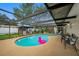 Screened-in pool area with a pink flamingo float, surrounded by lounge chairs and an outdoor kitchen, ideal for relaxation at 2329 Carrie Ct, Dunedin, FL 34698