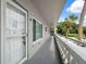 Exterior hallway with a white door, railing, and view of palm trees and parked cars at 2461 Rhodesian Dr # 47, Clearwater, FL 33763