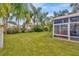 Large backyard with a screened-in patio, lush lawn, and tropical landscaping at 25101 Hyde Park Blvd, Land O Lakes, FL 34639