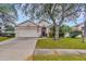 Charming single-story home featuring a well-manicured lawn, mature trees, and a two-car garage at 25101 Hyde Park Blvd, Land O Lakes, FL 34639
