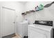 Laundry room featuring washer and dryer units, storage shelves, and tiled floor at 26343 Whirlaway Ter, Wesley Chapel, FL 33544