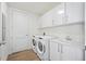 Well-equipped laundry room with modern appliances, cabinets, sink and door with paneled accents and wood floors at 301 1St S St # 1906, St Petersburg, FL 33701