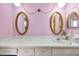 Retro-styled bathroom with lavender walls, decorative mirrors, and a long vanity with a white sink at 321 Belle View Ave, Temple Terrace, FL 33617