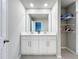 Bright bathroom with a double sink vanity, open storage, and a large mirror illuminated by recessed lighting at 32451 Limitless Pl, Wesley Chapel, FL 33545