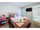 Bedroom with a pink-themed bed, TV, and carpet flooring, creating a cozy and cheerful space at 32451 Limitless Pl, Wesley Chapel, FL 33545