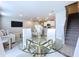 Modern dining area featuring a clear glass table, white chairs, and stairway views at 32451 Limitless Pl, Wesley Chapel, FL 33545