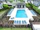 Aerial view of a sparkling community pool surrounded by lounge chairs, landscaping, and a secure fence at 32451 Limitless Pl, Wesley Chapel, FL 33545